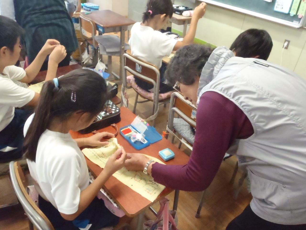 学校応援団の女性が生徒へ裁縫を教えている写真