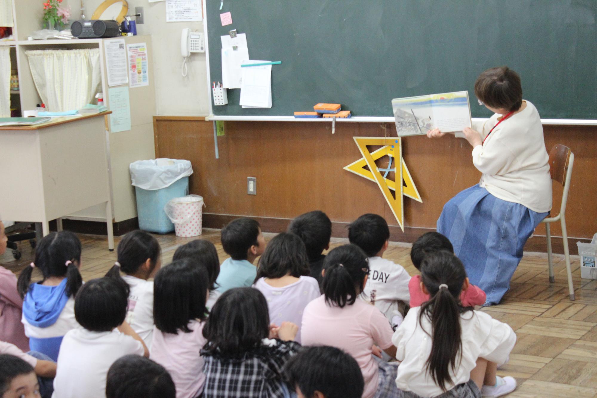 読み聞かせに聞き入る児童の写真